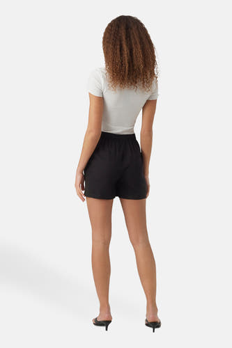 Short noir de VERO MODA, porté avec un haut blanc rayé et des chaussures noires, vu de derrière.