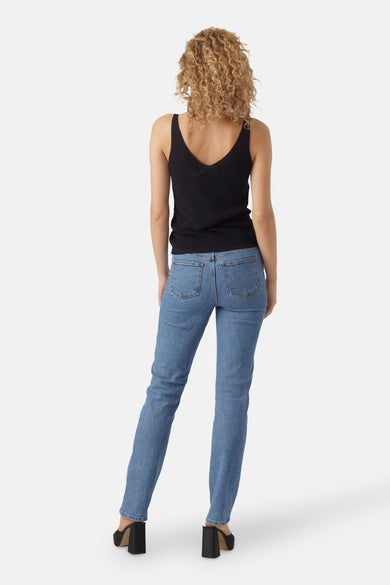 Top noir de VERO MODA, avec un décolleté en V, porté avec un jean bleu et des talons noirs.