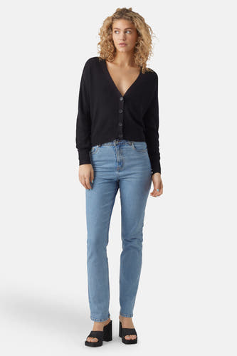 Zwart vest van Vero Moda, met lange mouwen en knoopsluiting, gecombineerd met blauwe jeans en zwarte plateauzolen.

