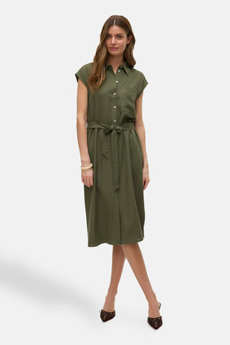 Vrouw in olijfgroene linnen jurk met riem en bruine schoenen.