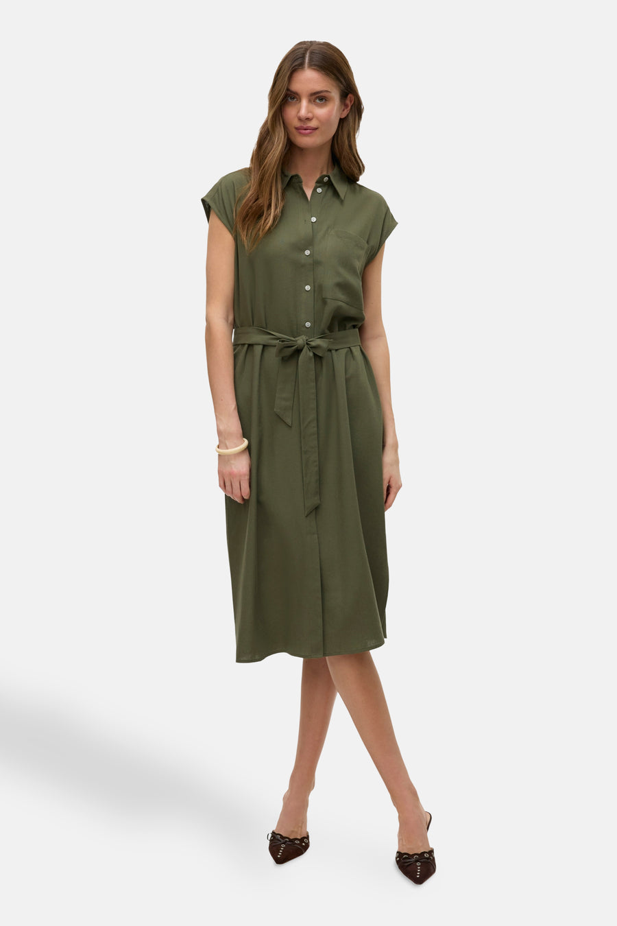 Vrouw in olijfgroene linnen jurk met riem en bruine schoenen.