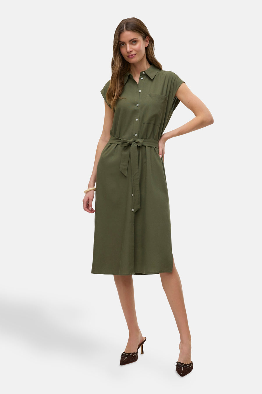 Vrouw in olijfgroene overhemdjurk met riem en bruine hakken.