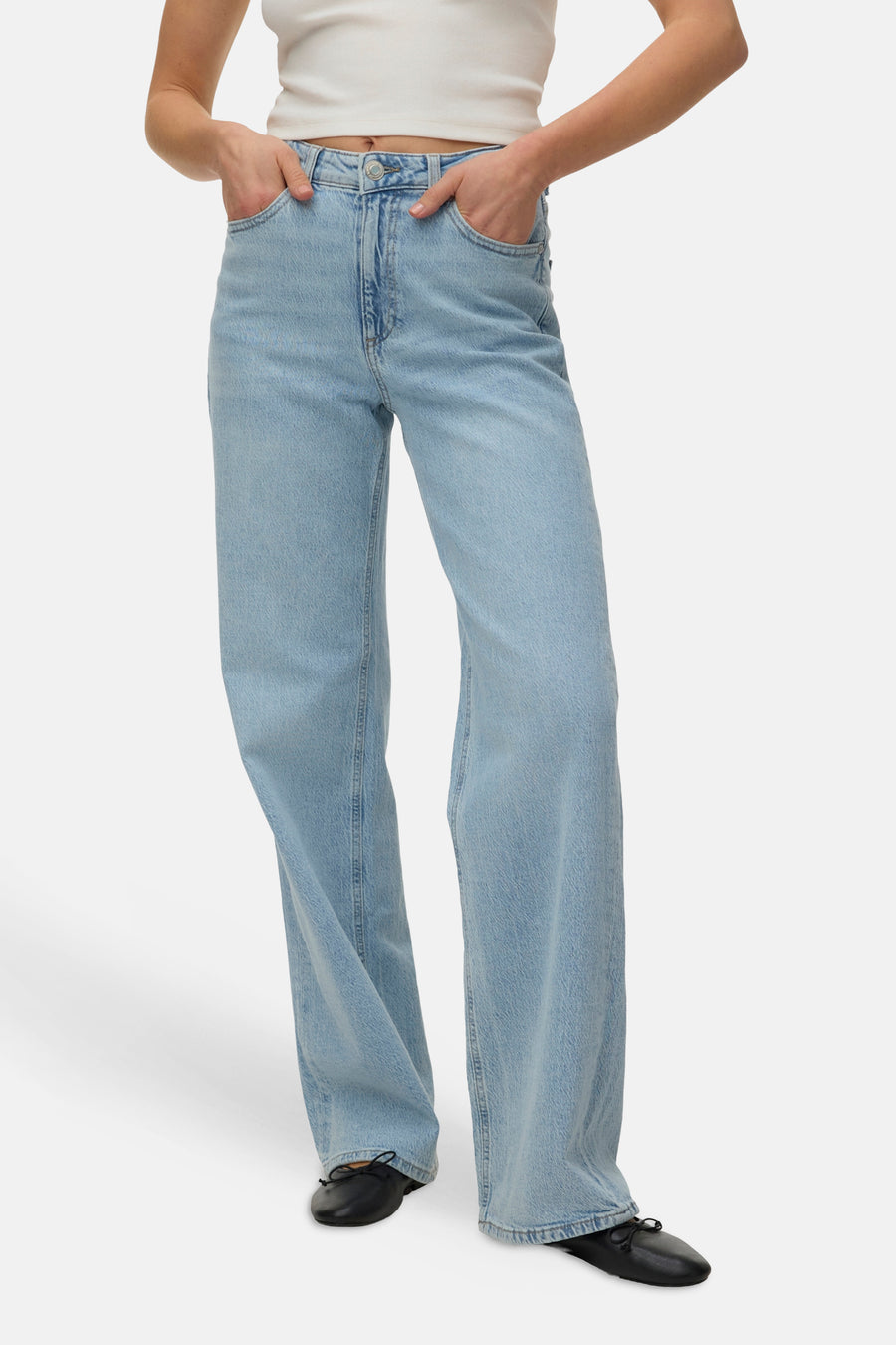 Jean droite bleu clair en denim de VERO MODA, à jambes larges et porté avec des ballerines noires.
