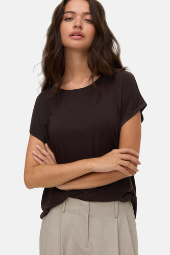 T-shirt brun à manches courtes de VERO MODA, porté avec un pantalon beige et les bras croisés.