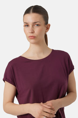 T-shirt violet à manches courtes de Vero Moda, avec des manches retroussées, porté par une femme avec des boucles d'oreilles en argent.