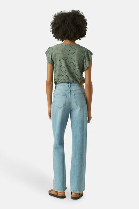 T-shirt vert avec manches courtes de VERO MODA, avec un motif perforé et porté avec un jean léger et des sandales brunes.