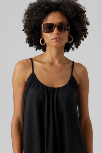 Robe sans manches noire de VERO MODA, avec des rubans spaghetti, associée à de grandes boucles d'oreilles rondes et un chapeau de soleil.