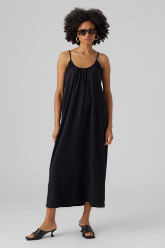 Robe noire sans manches de VERO MODA, avec des bretelles spaghetti et portée avec des sandales noires et un chapeau de soleil.