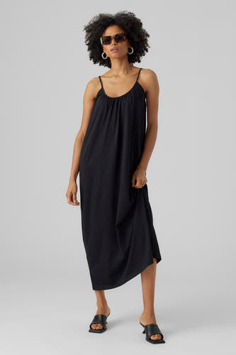 Robe sans manches noire de VERO MODA, avec des jarretelles spaghetti et portée avec des bottes noires et un chapeau de soleil.