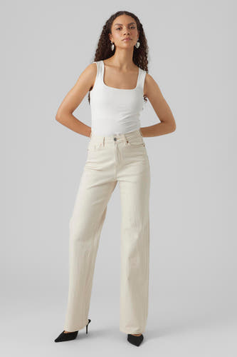 Off-white denim jeans wide van VERO MODA, gedragen met een wit hemdje en zwarte hakken.