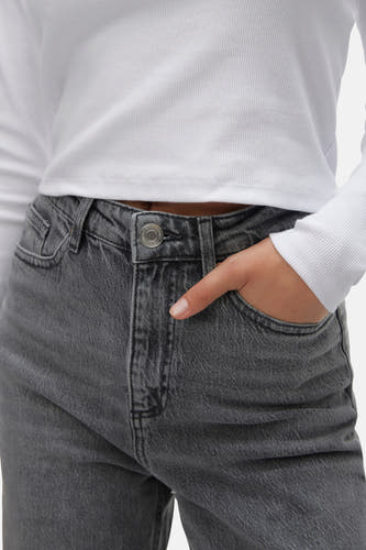 Jean gris large de Vero Moda, avec la main dans la poche et une chemise blanche.