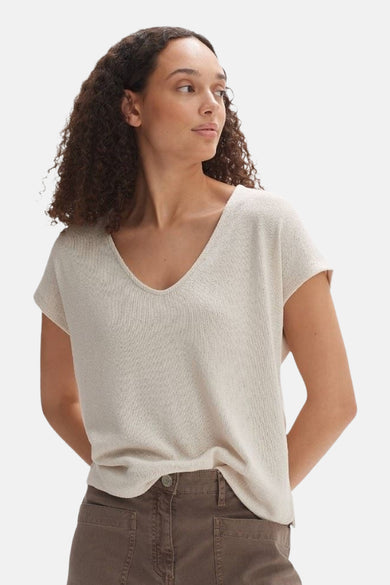 Blouse écru à manches courtes d'OPUS, avec un col V et portée avec une jupe brune.