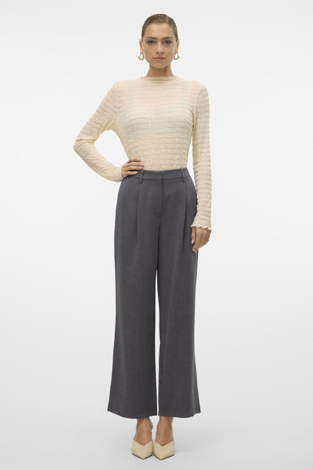Grijze broek van VERO MODA, uitlopende pijpen, hoge taille, gecombineerd met een crèmekleurige top en puntige schoenen.
