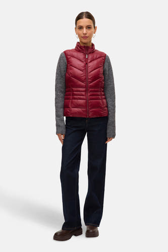 Gilet rouge de VERO MODA, avec un design tricoté, porté sur une chemise grise et des jeans foncés.