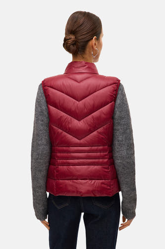 Gilet rouge de VERO MODA porté sur une chemise grise et des jeans foncés.