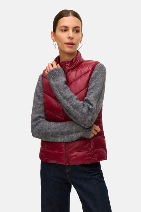 Gilet rouge de VERO MODA, avec un motif bouclé, porté sur une chemise grise et des jeans foncés.