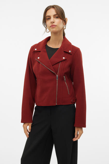 Manteau court brun de VERO MODA, vu de derrière, avec une jupe noire et des boucles d'oreilles dorées.