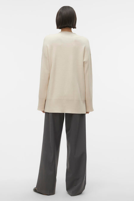 Gilet beige de VERO MODA, vu d'arrière, avec des manches longues et associé à un pantalon gris large.