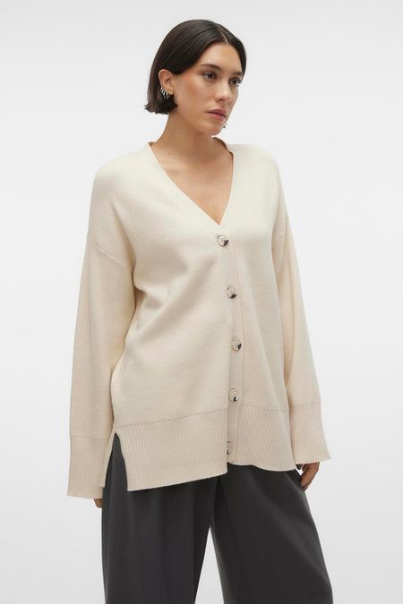 Gilet beige de VERO MODA, avec des boutons et des manches longues, porté sur un pantalon foncé.