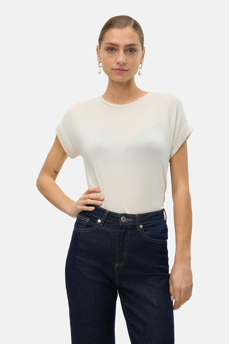 T-shirt beige à manches courtes de VERO MODA, porté avec des jeans bleu marine et des bottes brunes.