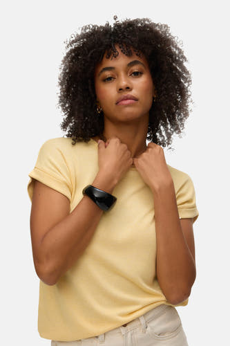 T-shirt jaune à manches courtes de VERO MODA, vu de l'arrière avec une main dans la poche arrière.