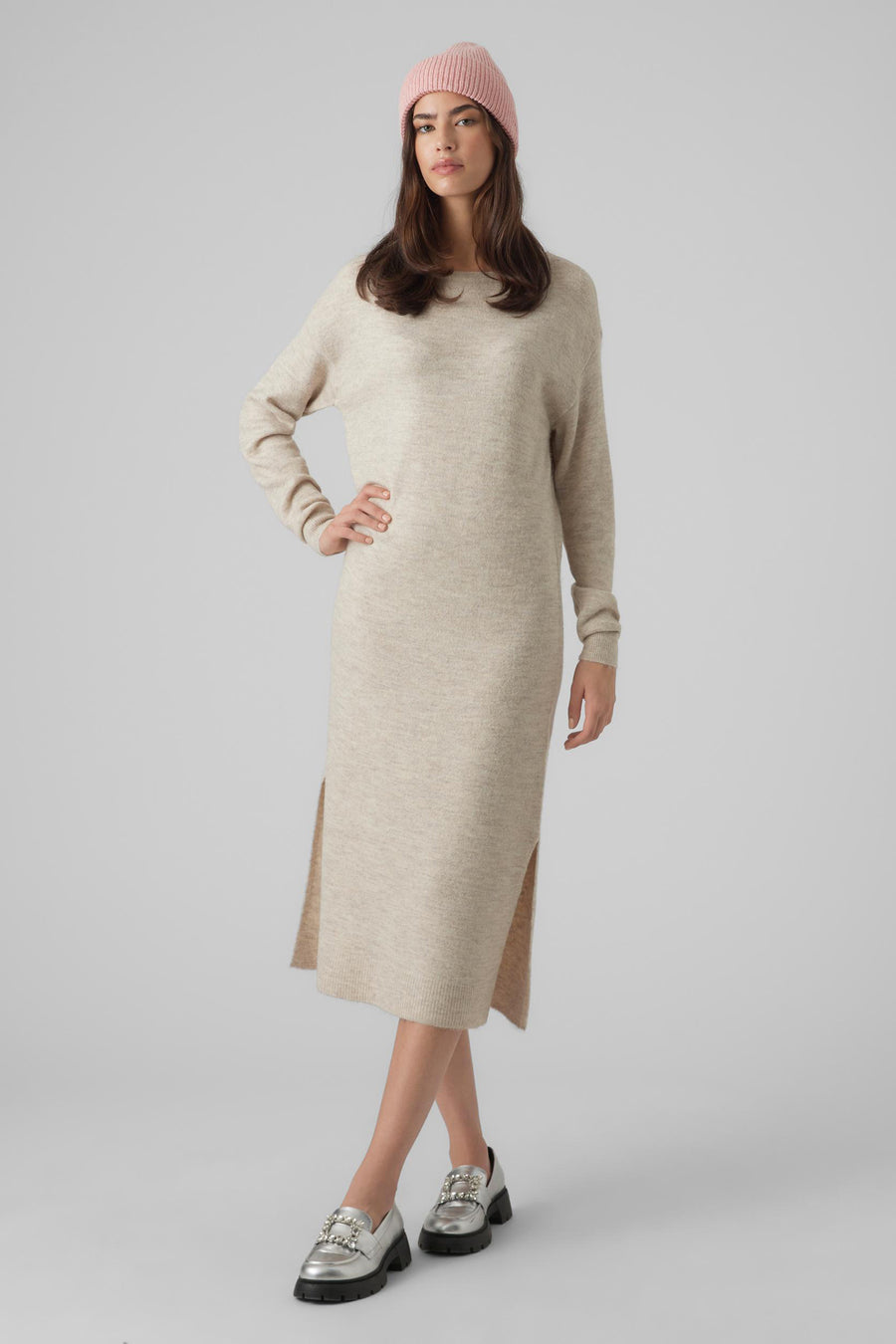 Manteau beige avec longues manches de Vero Moda, avec une fente latérale et associé à des loafers argentés et un unanie rose.