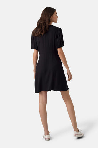 Robe noire à manches courtes de VERO MODA, vue de derrière, associée à des baskets blanches.