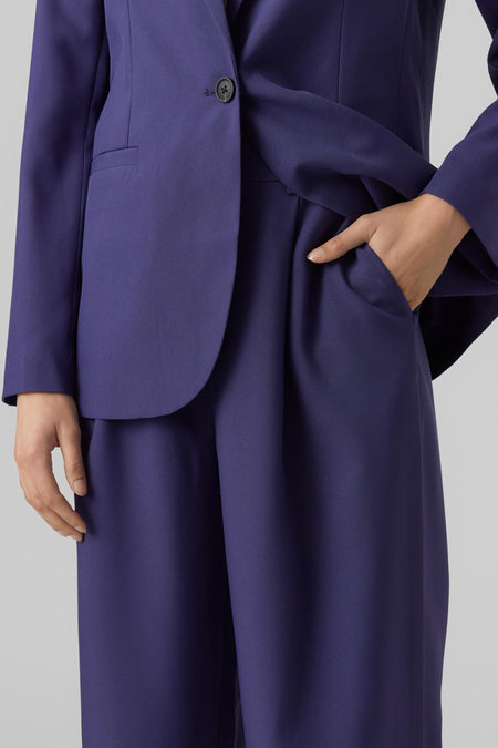 Pantalon bleu de VERO MODA, avec une main dans la poche et un blazer coordonné.
