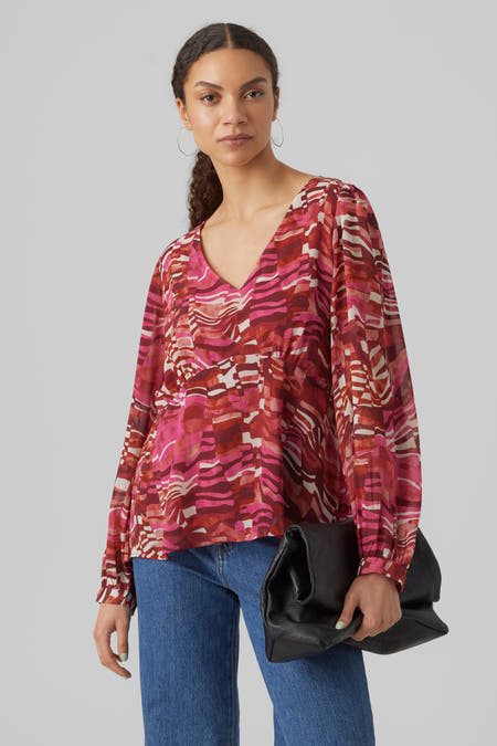 Blouse rose de VERO MODA avec motif abstrait, manches longues et associée à des jeans et une handte noire.