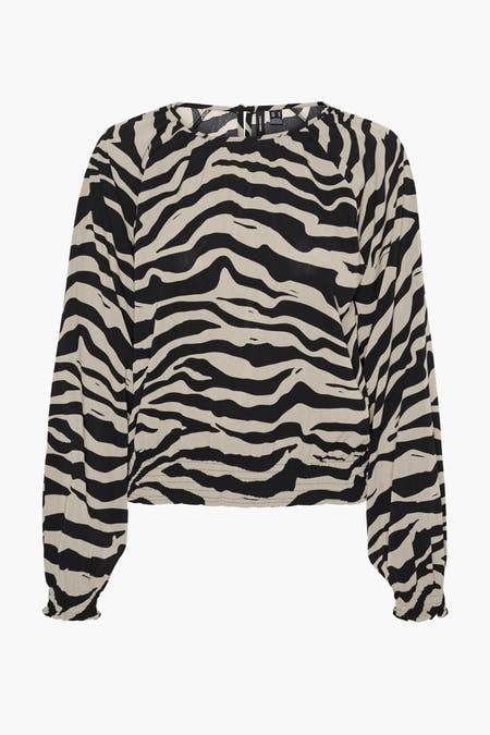 Blouse beige de VERO MODA avec imprimé zèbre et longues manches, associée à des jeans foncés et des escarpins noirs.