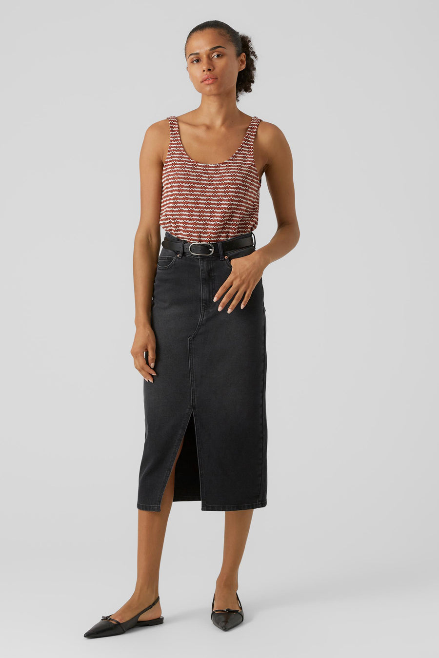 Zwarte rok van VERO MODA® met een split aan de voorkant, gecombineerd met een gestreepte top en zwarte slingback schoenen.