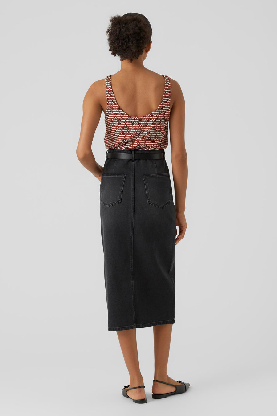 Robe noire de VERO MODA, avec une ceinture et des poches arrière, associée à un haut rayé.