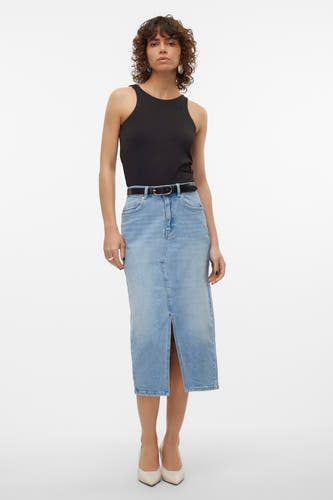 Jupe en denim bleu clair de VERO MODA, avec une fente et associée à un top noir et des chaussures blanches.