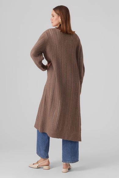 Bruine gilet van VERO MODA, met lange mouwen en opengebreide details, gecombineerd met een jeans en schoenen.

