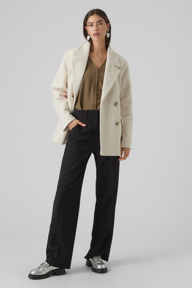 Bontjas couleur écru de VERO MODA® avec double boutonnage, large col, modèle en longueur complète avec pantalon noir et chaussures argentées