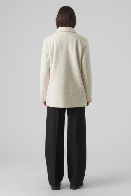 Veste courte écrue de VERO MODA®, texture douce, vue de dos, le modèle porte un pantalon large noir