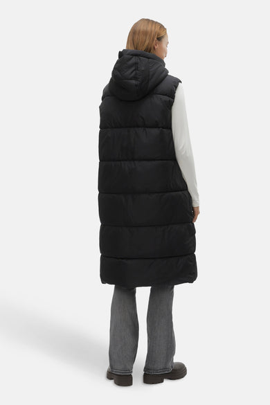 Zwarte mouwloze jas van VERO MODA®, gezien van achteren, met capuchon, gecombineerd met een wit shirt en grijze jeans.