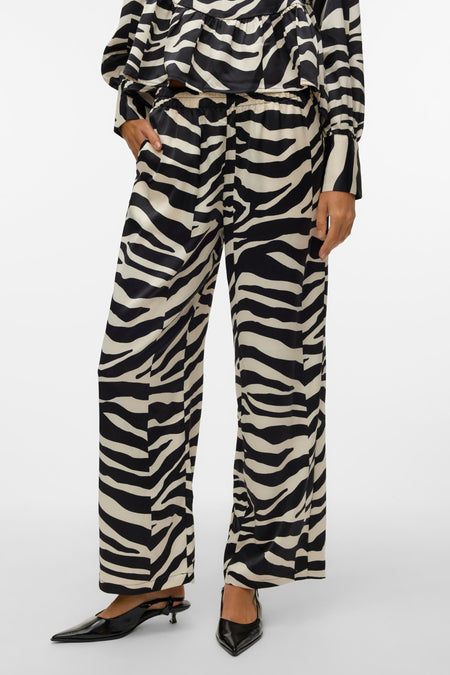 Zwarte broek van VERO MODA® met zebraprint en wijde pijpen, gecombineerd met zwarte pumps.
