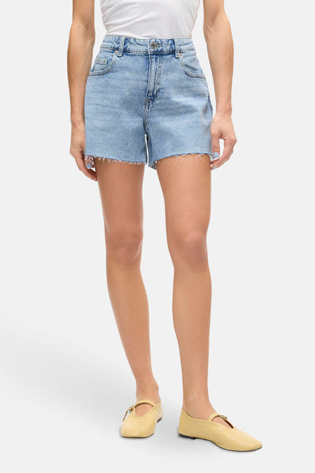 Short en denim bleu clair de VERO MODA, associé à un T-shirt blanc et des baskets jaune moutarde.