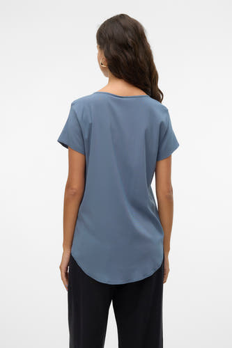 Blauw bloes met korte mouwen van VERO MODA, gezien van achteren, met donkerbruin golvend haar en zwarte broek.
