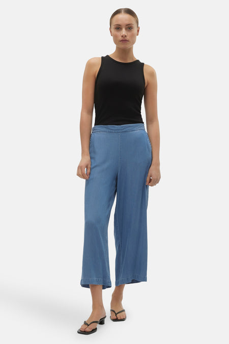 Jean bleu de Vero Moda, associé à une chemise noire et des sandales à talons.