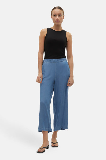 Jean bleu de VERO MODA®, avec des jambes larges et une coupe confortable, associé à un tanktop noir.