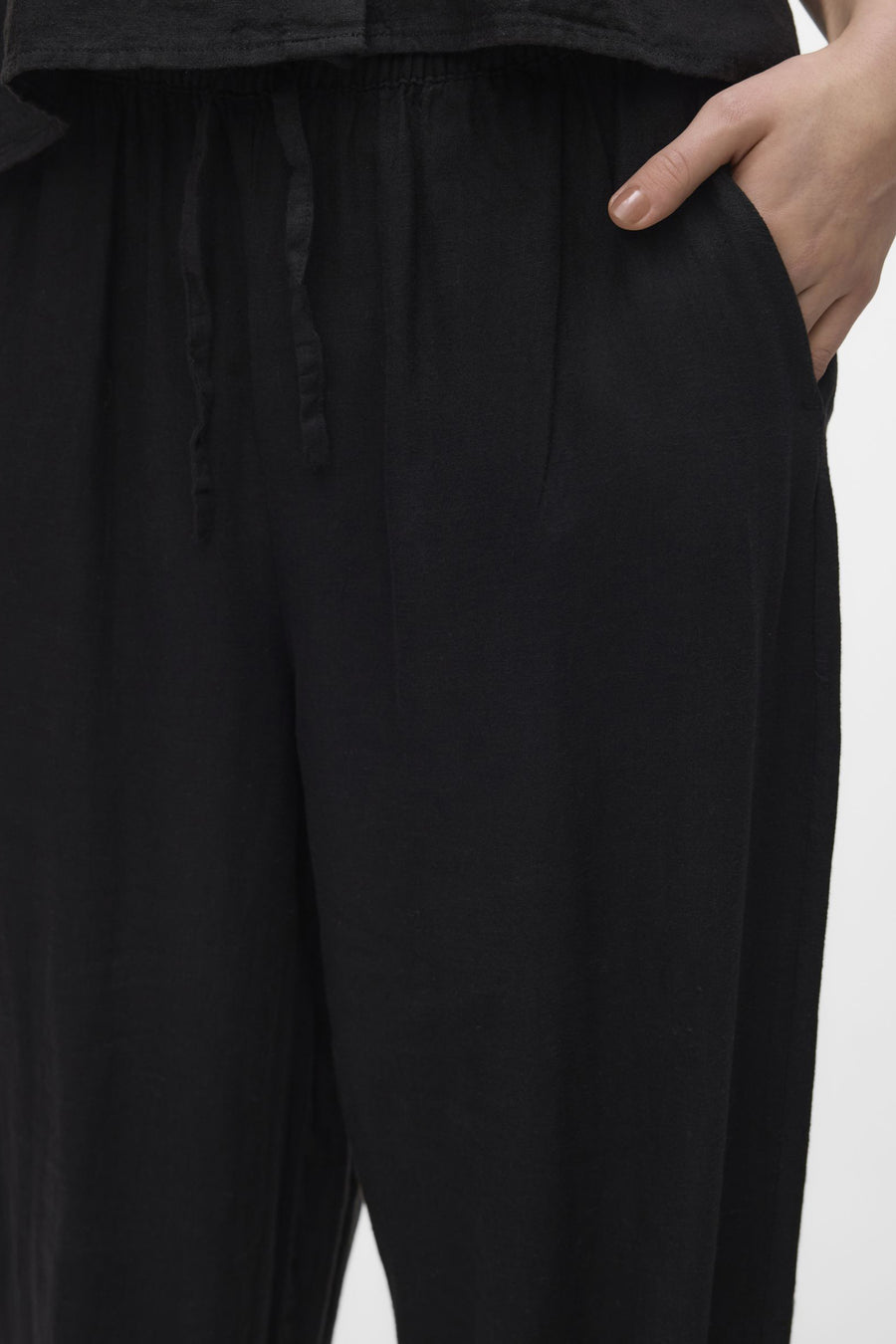 Pantalon noir de VERO MODA, avec cordon de serrage et une main dans la poche.