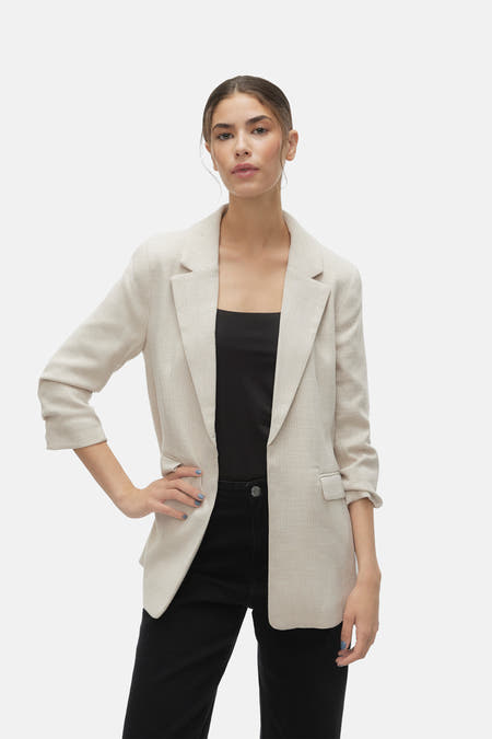 Blazer écru de VERO MODA®, vu de derrière, associé à un pantalon noir et des talons.