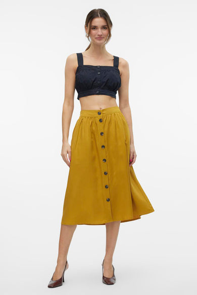 Blouse noire de VERO MODA, avec fermeture à boutons, associée à une jupe marron avec boutons et lacets.