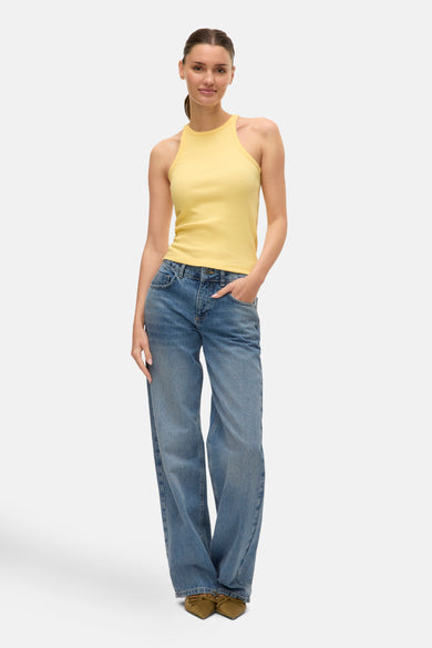 Gele top van VERO MODA, gecombineerd met een blauwe jeans en olijfgroene schoenen.