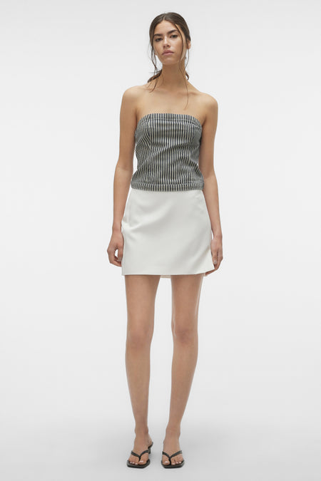 Blauwe blouse van VERO MODA, gecombineerd met een witte rok en zwarte sandalen.
