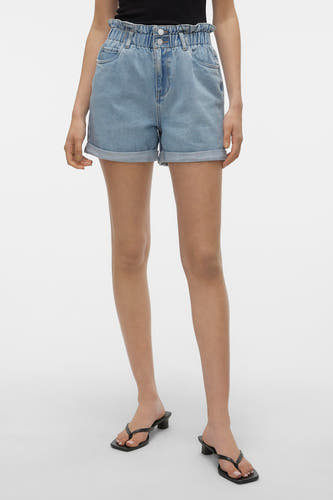 Short en jean bleu de VERO MODA® avec taille paperbag élastique haute, ourlets retroussés et poches arrière.Vue de dos, portée avec un haut noir et des mules.