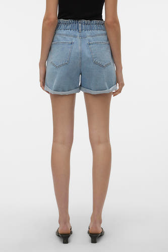 Blauwe denim short van VERO MODA® met hoge elastische paperbag taille, omgeslagen pijpen en achterzakken. Van achteren gezien, gedragen met een zwarte top en muiltjes.