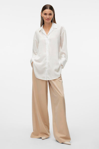 Wit, gestreept hemd met lange mouwen van VERO MODA®, gedragen met beige, wijde broek en zilveren oorbellen.